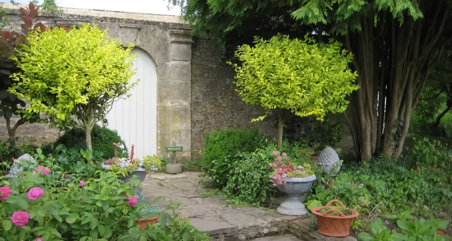 Elegant garden entrance with stone archway, colorful flowers, and ornamental planters
